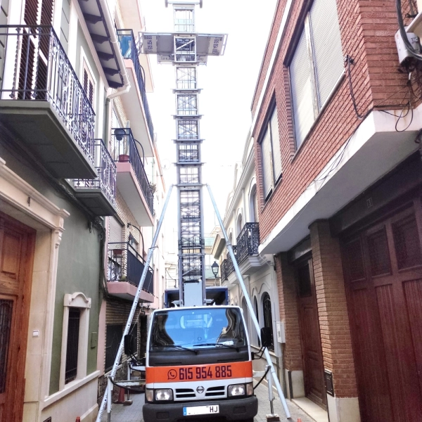 Fotografía de una mudanza con una plataforma elevadora a un tercer piso en una calle estrecha